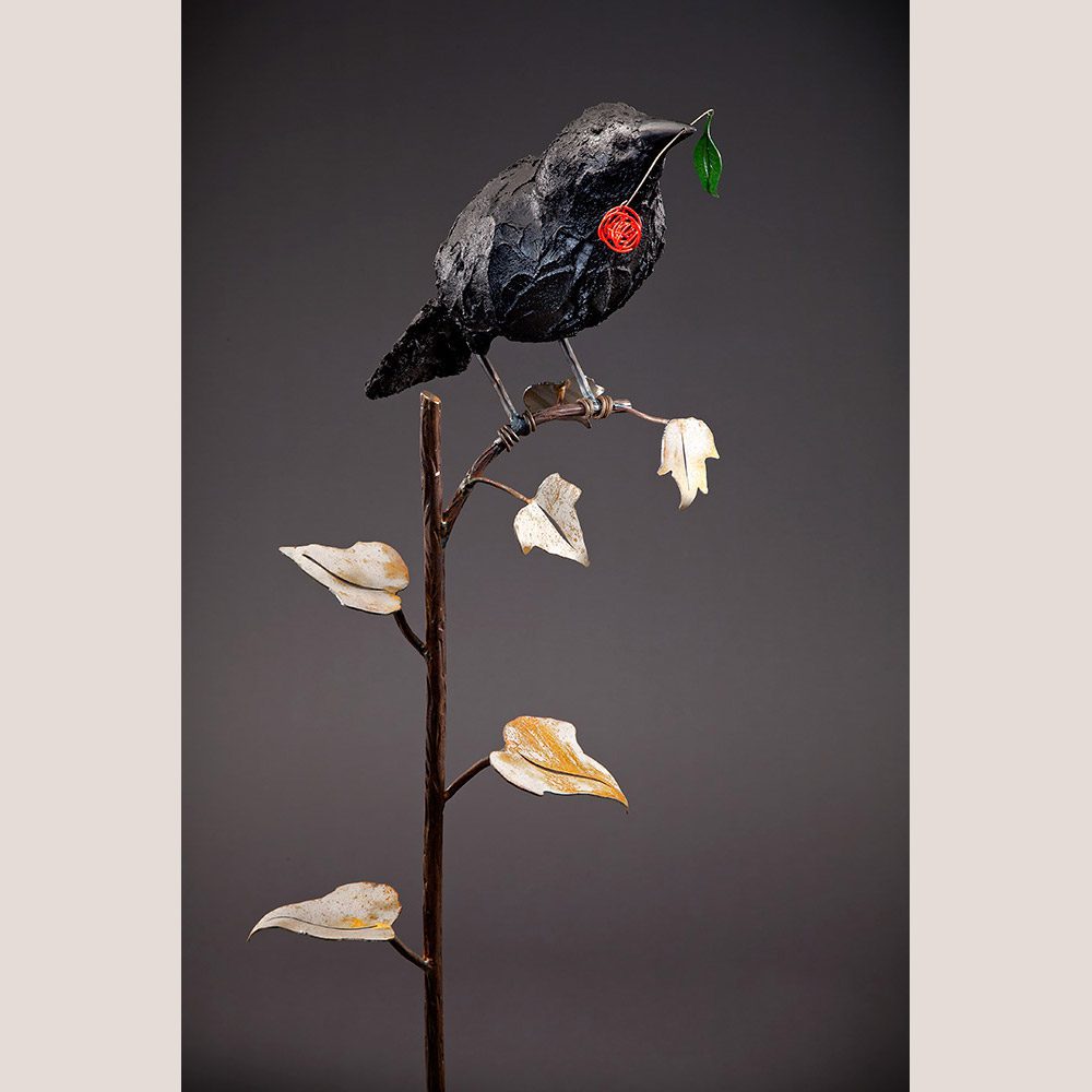 Black bird sitting on a leaf metal product